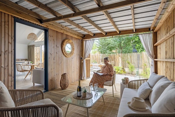A cozy outdoor seating area with wicker furniture, a glass table, and a wooden ceiling.