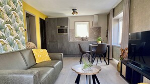 Un salon moderne avec un canapé gris, une table basse ronde et un téléviseur.