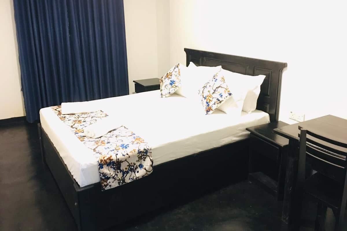 A neatly made bed with floral bedding, a bedside table, and a chair in a hotel room.