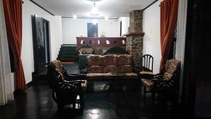 Ein Zimmer mit einer Sofagarnitur, zwei Sesseln, einem kleinen Tisch und einer Treppe, die in eine obere Ebene führt.