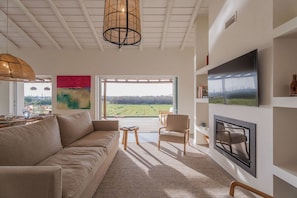 A modern living room with a sofa, chairs, a TV, and a large window with a view. - Casa Terracotta (Alcacer do Sal)