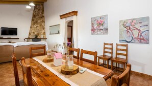 Ein Essbereich mit einem Holztisch, Stühlen, einem Fernseher und einer Steinwand.