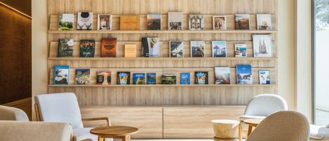 A modern interior with a wall of bookshelves, comfortable seating, and a wooden floor.