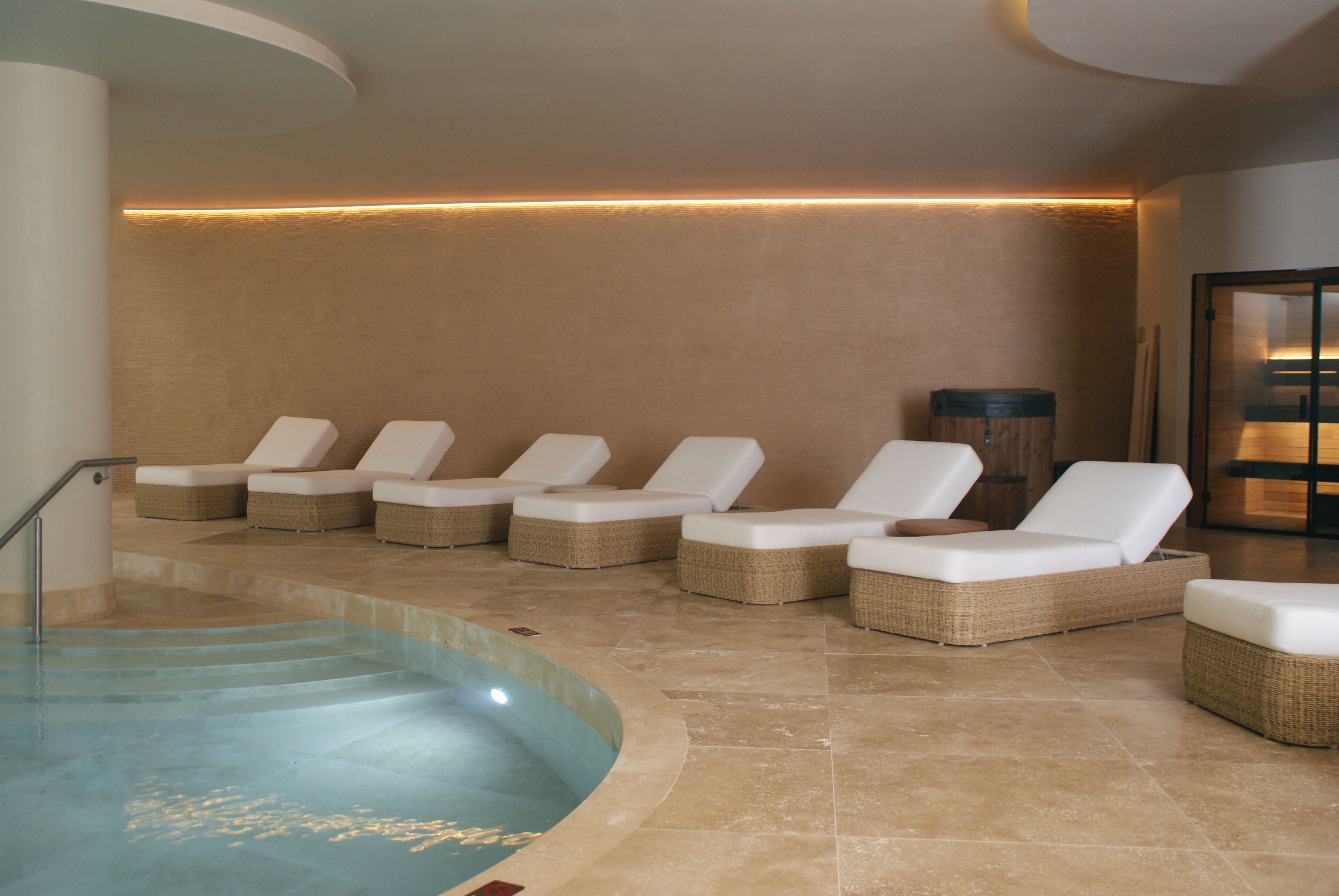 A spa area with a pool, lounge chairs, and a massage room.