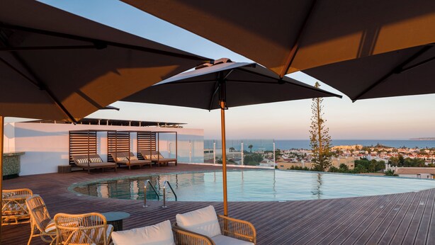 A rooftop pool area with lounge chairs and umbrellas, overlooking a coastal town. - Castelo Suites Hotel (Albufeira)