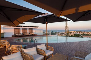A rooftop pool area with lounge chairs and umbrellas, overlooking a coastal town. - Castelo Suites Hotel (Albufeira)