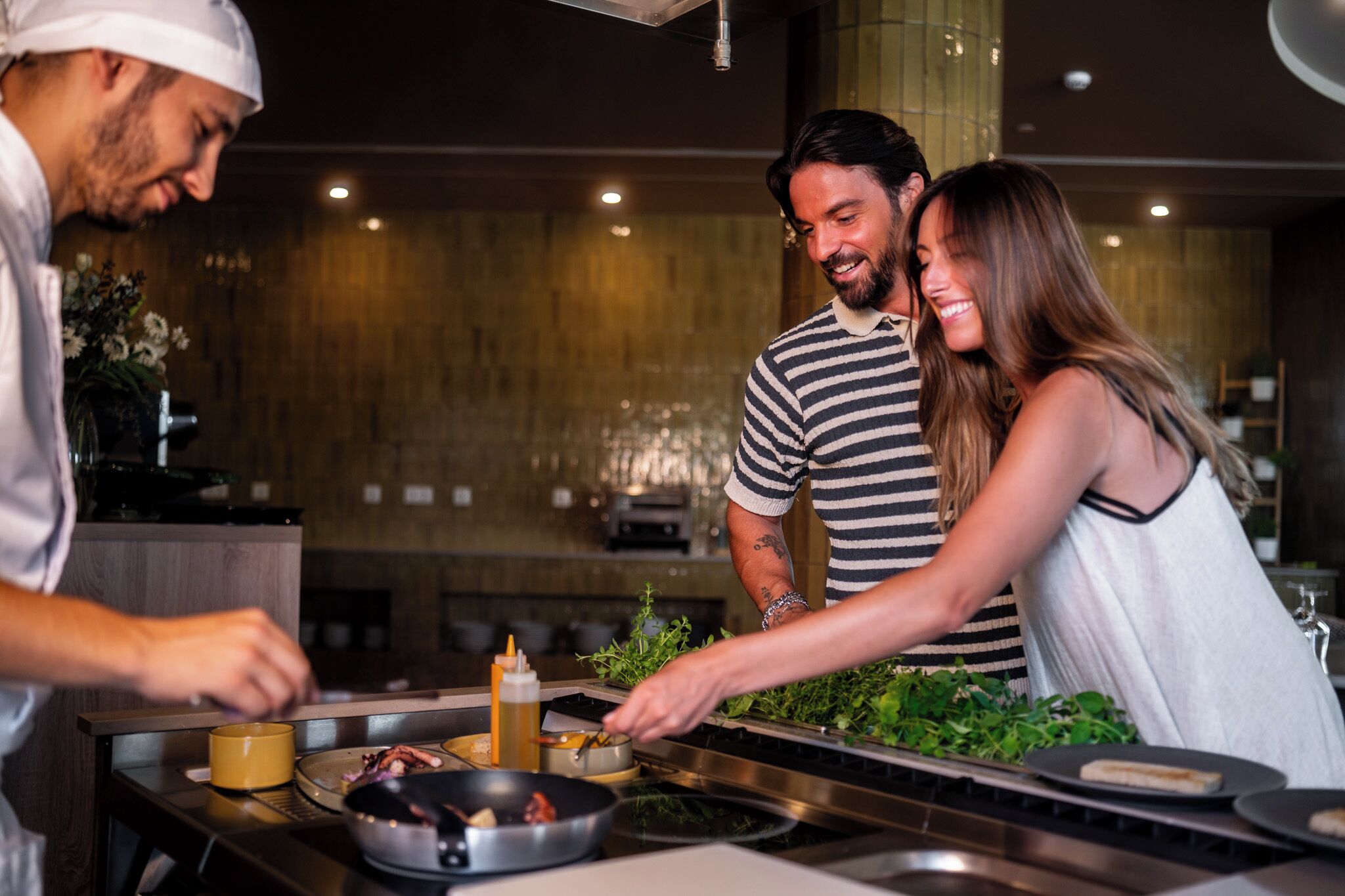 A modern kitchen with stainless steel appliances, a wooden countertop, and a person cooking.