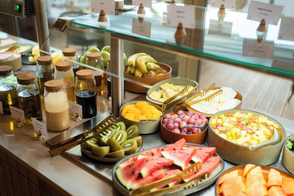 Un bufé de desayuno con diversas frutas, quesos y bebidas.