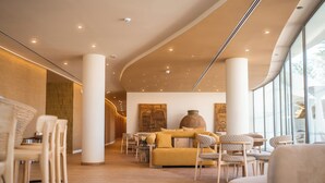 A modern interior with a curved ceiling, wooden flooring, and a seating area with a sofa and chairs. - Castelo Suites Hotel (Albufeira)