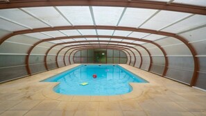 En indendørs swimmingpool med buet loft og flisegulv.