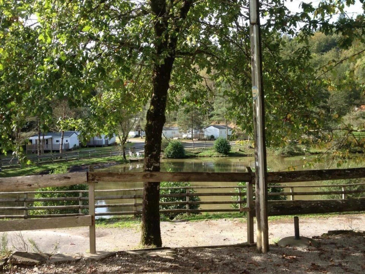 A wooden fence with a view of a pond and houses in the background.