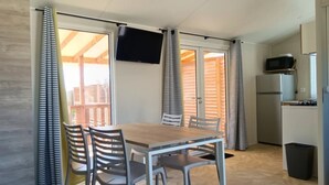 Eine kleine Küche mit Mikrowelle, Kühlschrank und einer Essecke mit Tisch und Stühlen.