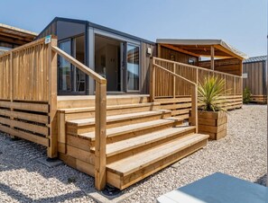Un bâtiment moderne en bois, doté d’un escalier menant à une entrée avec une porte en verre.