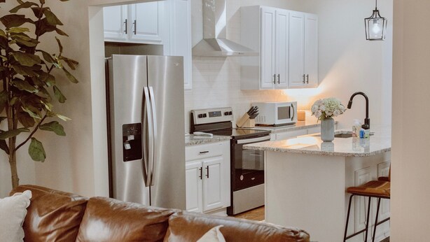 Una cocina moderna con gabinetes blancos, electrodomésticos de acero inoxidable y una isla central.