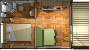 Une petite pièce avec un plancher en bois, un lit, une petite table, une chaise, des toilettes et un lavabo.
