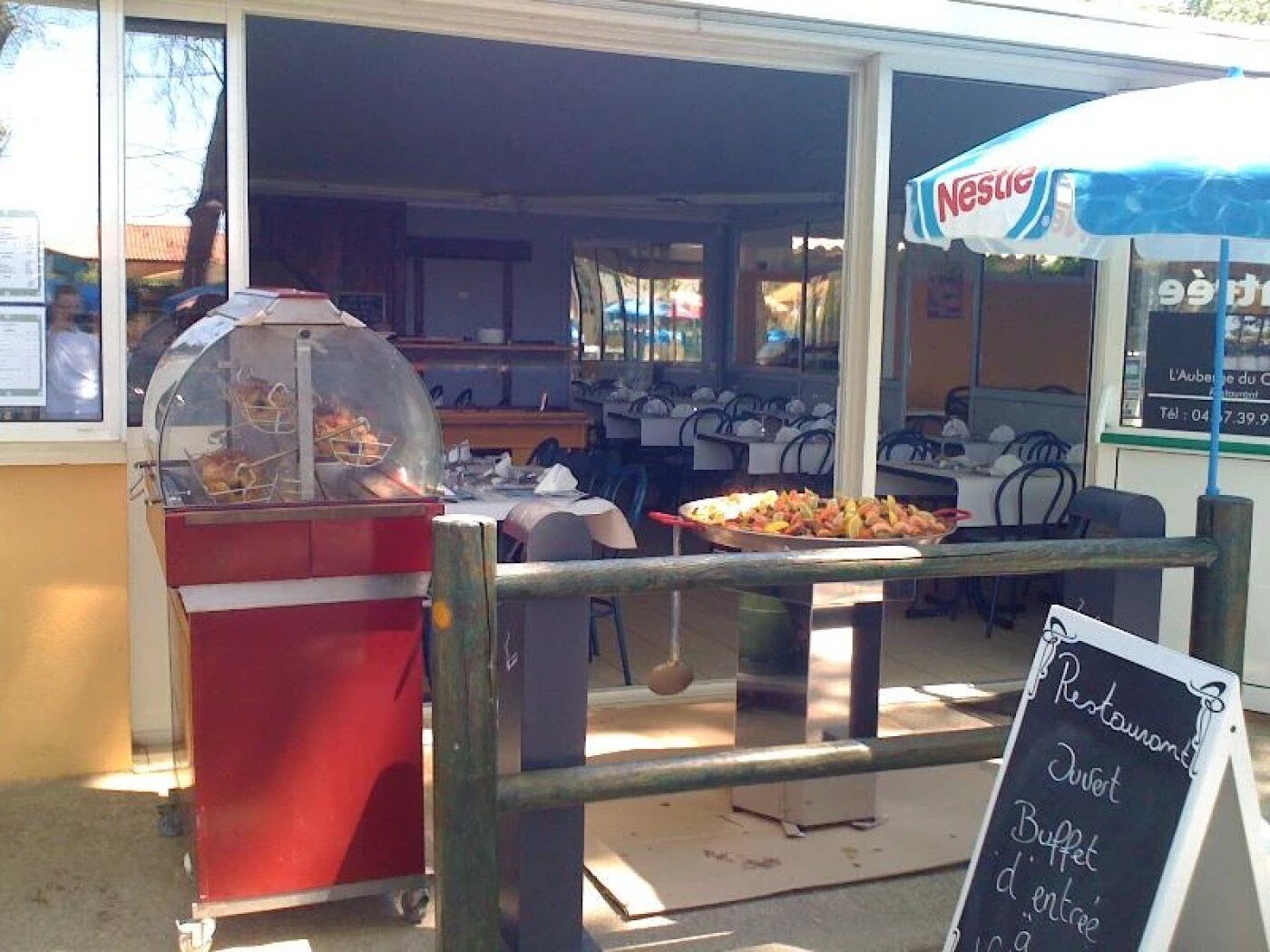 Een openluchtrestaurant met een buffetbord, een Nestlé-ijsstand en een etalage met eten.