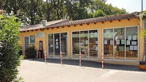 A building with a yellow facade, large glass windows, and a tiled roof.