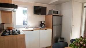 A compact kitchen with a gas stove, a microwave, a coffee maker, and a refrigerator.