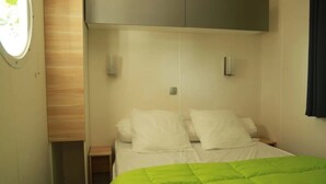 Un dormitorio compacto con cama, colcha verde y armario empotrado.