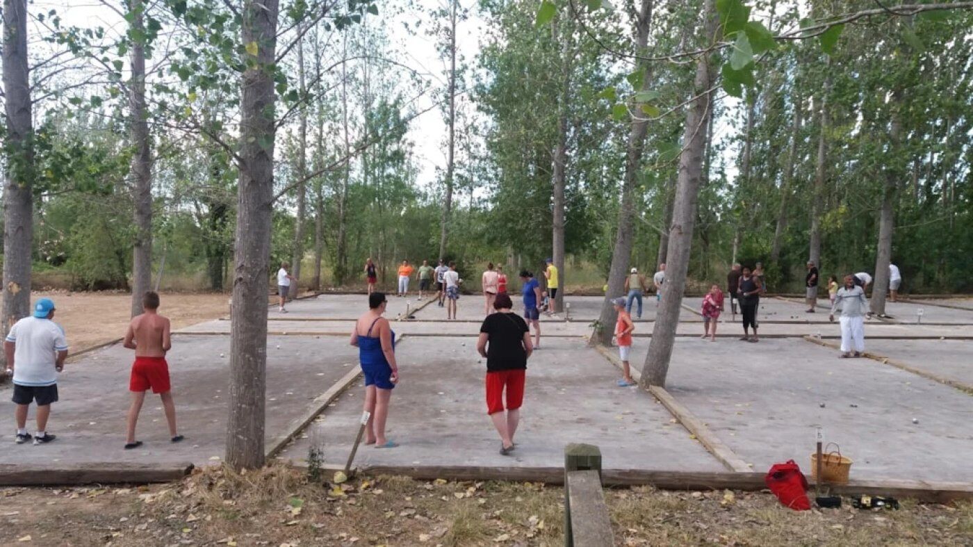 A group of people in an outdoor area with trees and a paved surface.