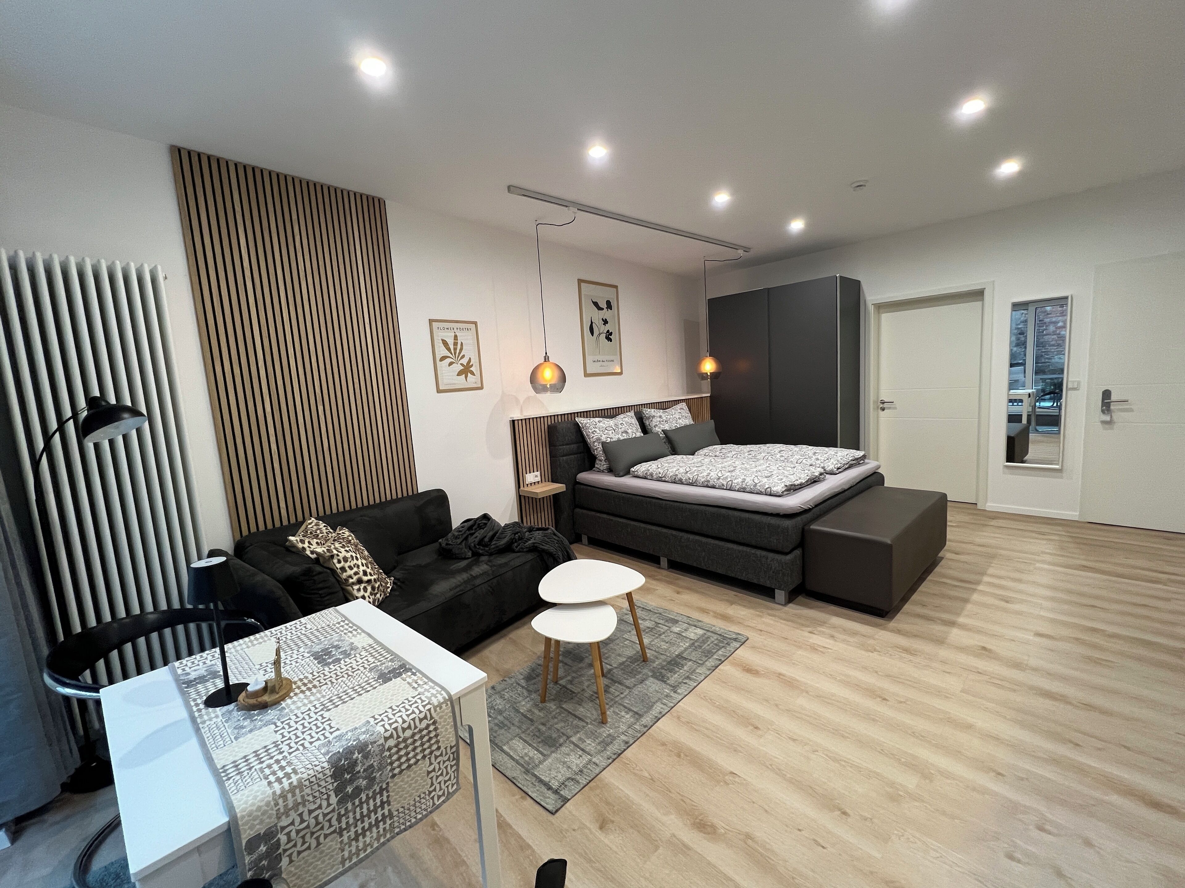 Ein modernes Schlafzimmer mit Bett, einer Couch, einem kleinen Tisch und einer Heizung.