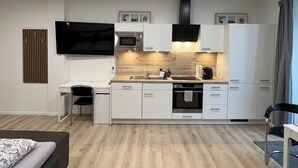 A modern kitchen with white cabinets, a built-in oven, microwave, and a large window with curtains.