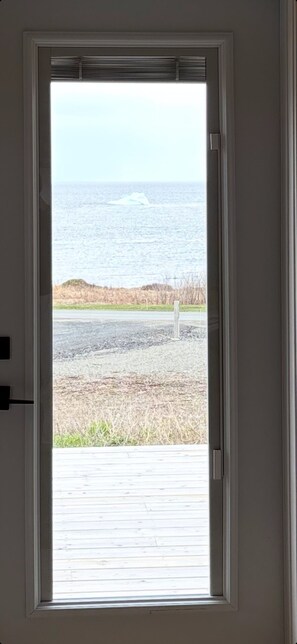 A door with a view of the ocean and a grassy area. - Blue Jellybean: Great ocean views and sunsets close to town. (Twillingate)