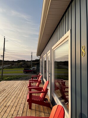 A wooden deck with red chairs and a glass door with the number 8.