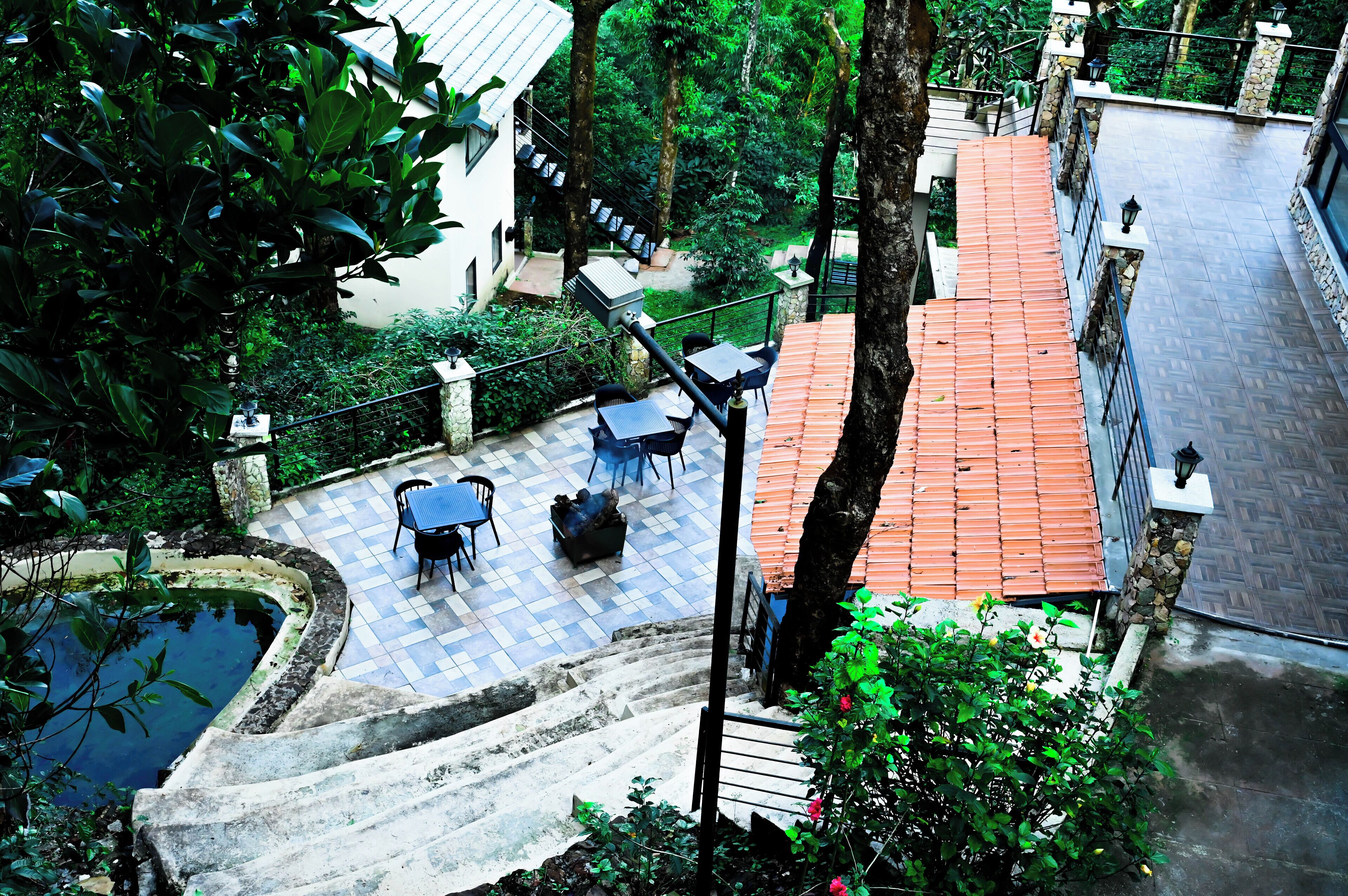 Ein Innenhof mit Pool, Sitzgelegenheiten im Freien und einer Treppe zu einem Gebäude mit rotem Dach.
