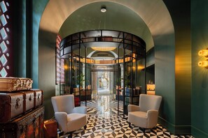 A lobby with a geometric patterned floor, a circular bookshelf structure, and vintage suitcases. - The Goethe Hotel - Small Luxury Hotels of the World (Rome)
