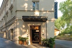 A hotel entrance with a wooden door, potted plants, and a sign indicating 'The Goth Hotel.'