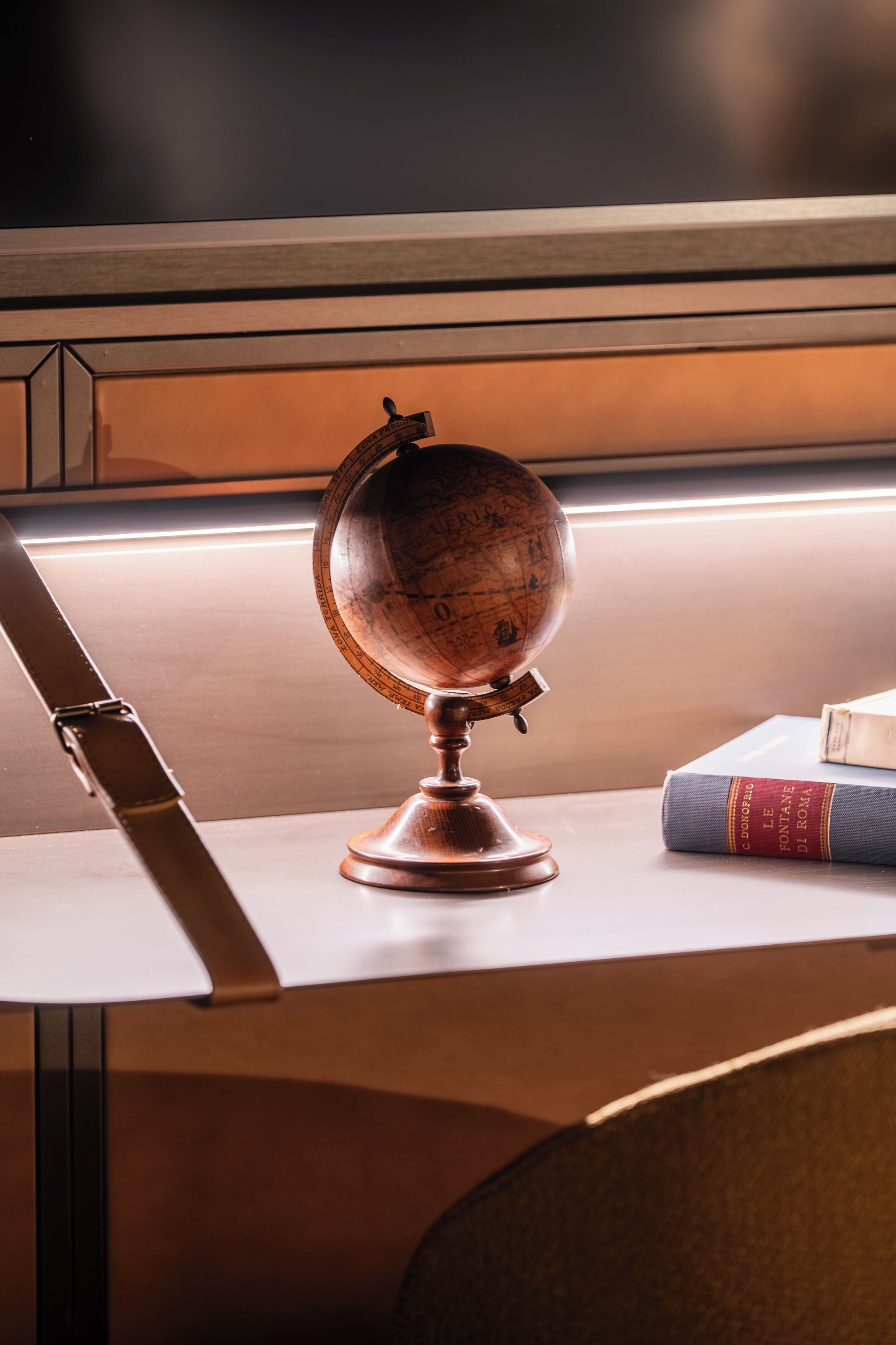 A globe on a wooden stand, a book, and a chair.