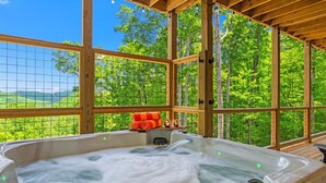 A hot tub in a wooden cabin with a view of a forest. - Top 1%, Pickleball, Sauna, Hot Tub, Near Dollywood (Sevierville)