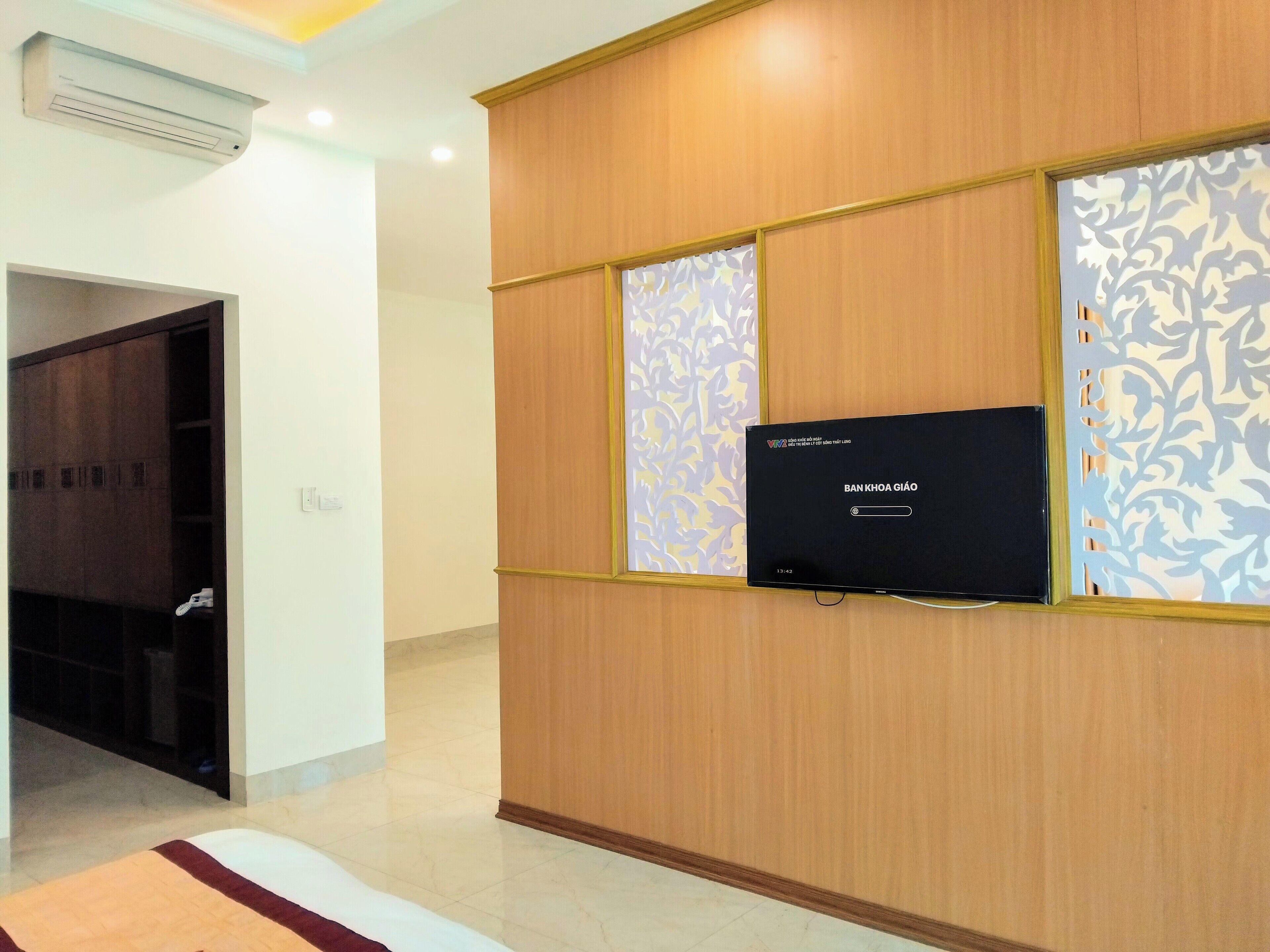 A modern room with a flat-screen TV mounted on a wooden wall, a patterned decorative panel, and a door leading to another area.