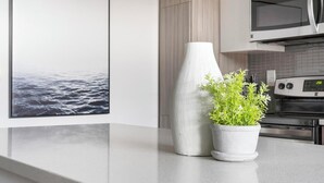 A kitchen with a white countertop, a white vase, and a potted plant. - Landing | Spectacular 2BD, Pool, Gym (Atlanta)