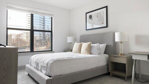 A bedroom with a bed, nightstands, and a desk. - Landing | Spectacular 2BD, Pool, Gym (Atlanta)