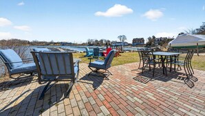 A patio area with outdoor seating, a table, and a view of the water and boats. - Cozy Waterfront Cottage (Noank)
