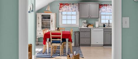 A spacious living room with a dining area, a kitchen, and a view through an open doorway.