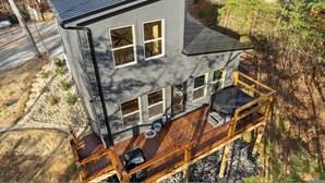 Une maison à deux étages dotée d’une terrasse et d’un espace extérieur aménagé et couvert.