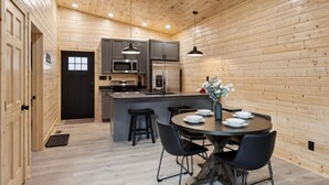 Une cuisine moderne avec des murs en bois, un îlot central et des tabourets de bar noirs.