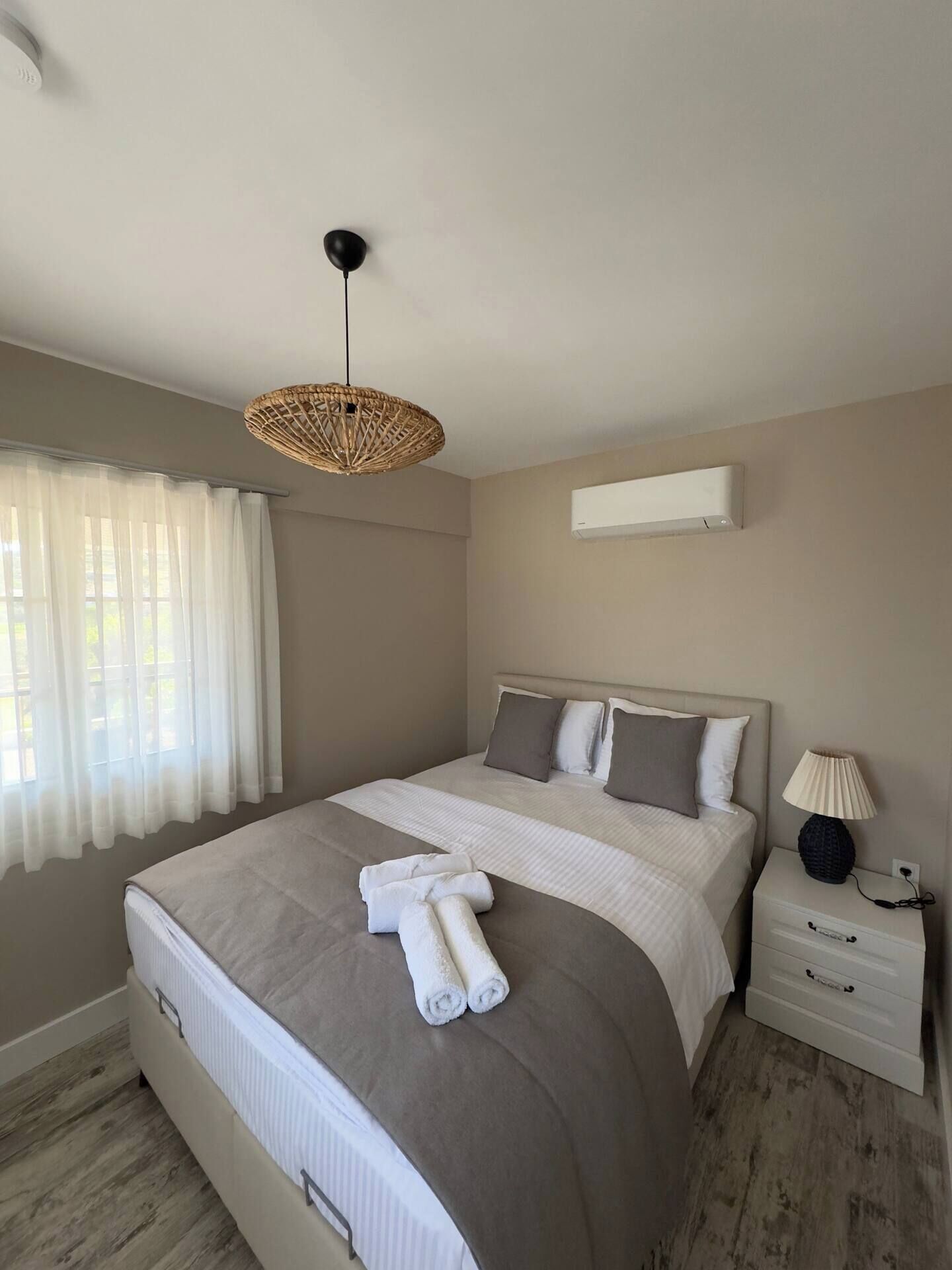 Un dormitorio ordenado con una cama grande, una mesita de noche con lámpara y un aplique de techo.