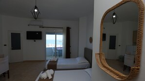 A hotel room with two beds, a television, and a view of the sea. - Michelle Apartments (Ksamil)