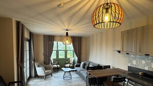 Ein modernes Wohnzimmer mit Essbereich, einer Küche und großen Fenstern.