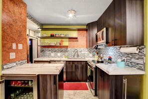 Enjoy cooking and dining in this well-equipped kitchen with a refrigerator, oven, microwave, and coffee machine.
