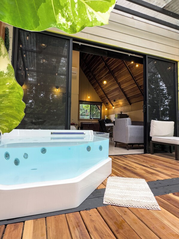 A hot tub on a wooden deck with a view of a modern interior space. - River Paradise Cabin with Private Jacuzzi (Provincia de Alajuela)