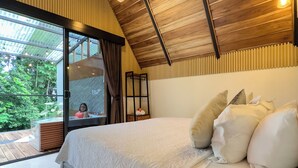 Un dormitorio con una cama grande, techo de madera y vistas a zonas verdes.