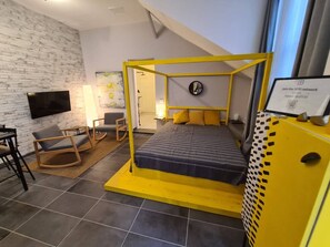 A modern hotel room with a bed, a desk, and a chair.