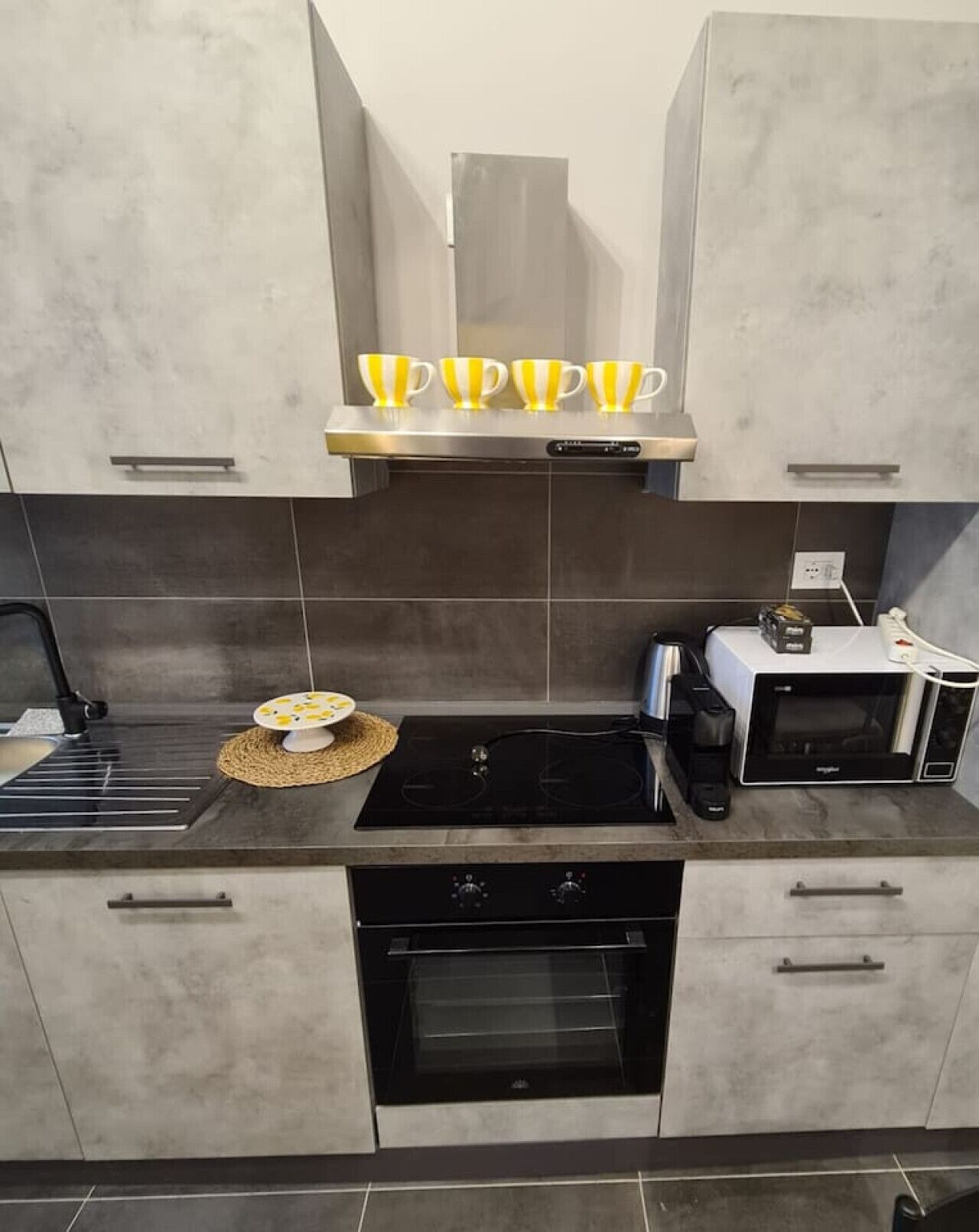 Une cuisine moderne équipée d’un four encastré, d’un four à micro-ondes et d’une plaque de cuisson.
