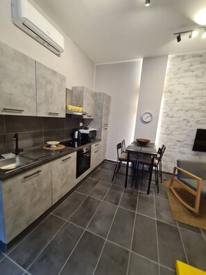 A modern kitchen with grey cabinets, a built-in oven, and a dining area with a table and chairs.