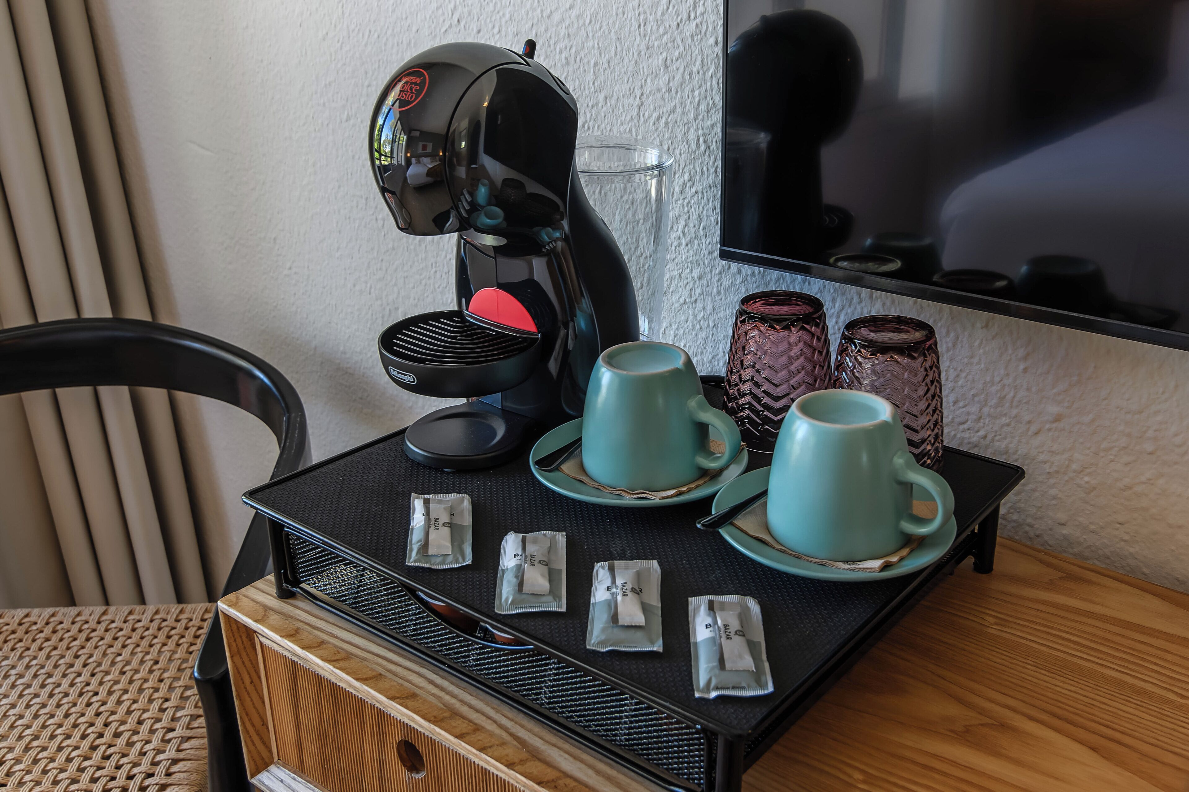 Une machine à café sur un plateau, avec deux tasses et des sachets de sucre.